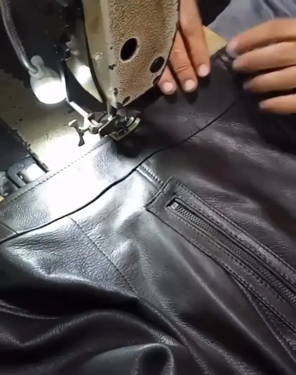 Artisans hand-stitching leather jacket